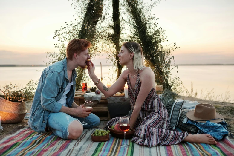 a man and a woman sitting next to each other on a blanket, pexels, at the waterside, promotional image, eating, romantic themed