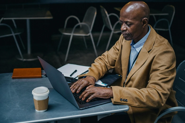 a man sitting at a table using a laptop computer, by Carey Morris, pexels contest winner, emmanuel shiru, lightly dressed, older male, people at work