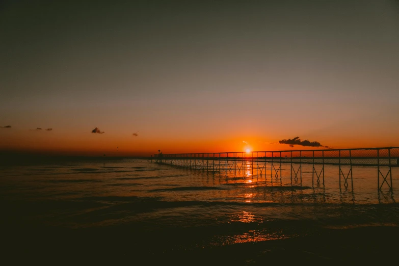 the sun is setting over the water at the beach, by Niko Henrichon, pexels contest winner, plain background, long view, brown, manly