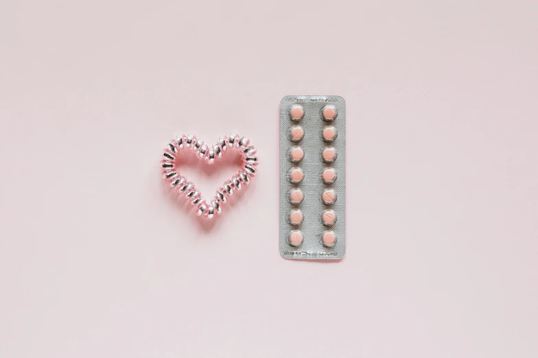 two pills and a heart on a pink background, by Emma Andijewska, trending on pexels, minimalism, copper spiral hair decorations, made out of shiny silver, screws, bubblegum body