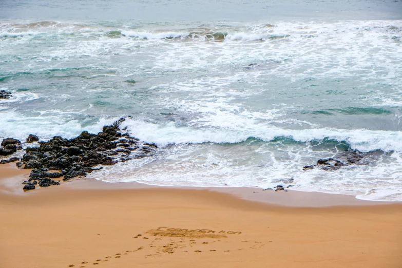 a man standing on top of a sandy beach next to the ocean, pexels contest winner, renaissance, bulli, footprints in the sand, rocky coast, today\'s featured photograph 4k