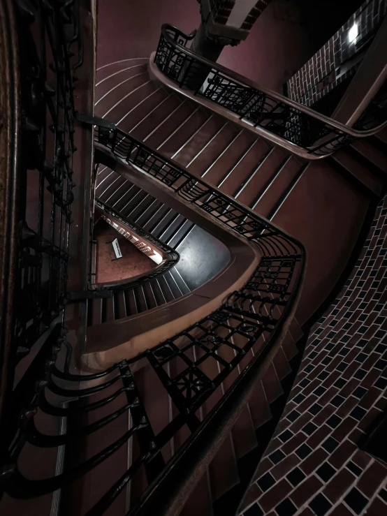 a spiral staircase in a building at night, inspired by M. C. Escher, unsplash contest winner, art nouveau, maroon, ignant, high - angle, intricate details photograph