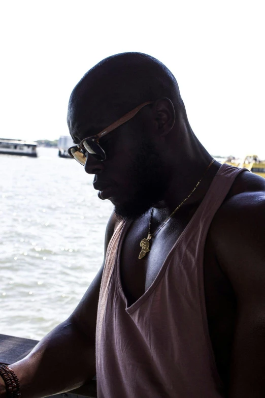 a man on a boat looking at his cell phone, an album cover, inspired by Michael Ray Charles, pexels contest winner, muscular bald man, notorious big, profile pic, black skin