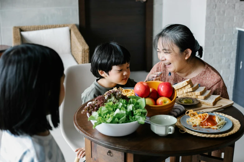 a woman and a child sitting at a table with food, pexels contest winner, fruit bowl, avatar image, asian woman, husband wife and son