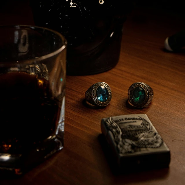 a couple of rings sitting on top of a wooden table, a still life, by Elsa Bleda, saturday night in a saloon, black and blue, 1960s color photograph, embedded with gemstones