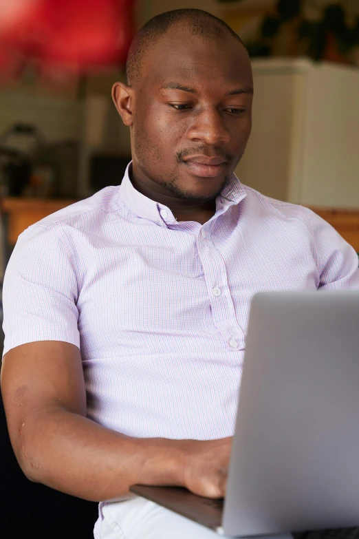 a man sitting on a couch using a laptop computer, pexels, wearing purple undershirt, photo of a black woman, wearing a white button up shirt, pastel'