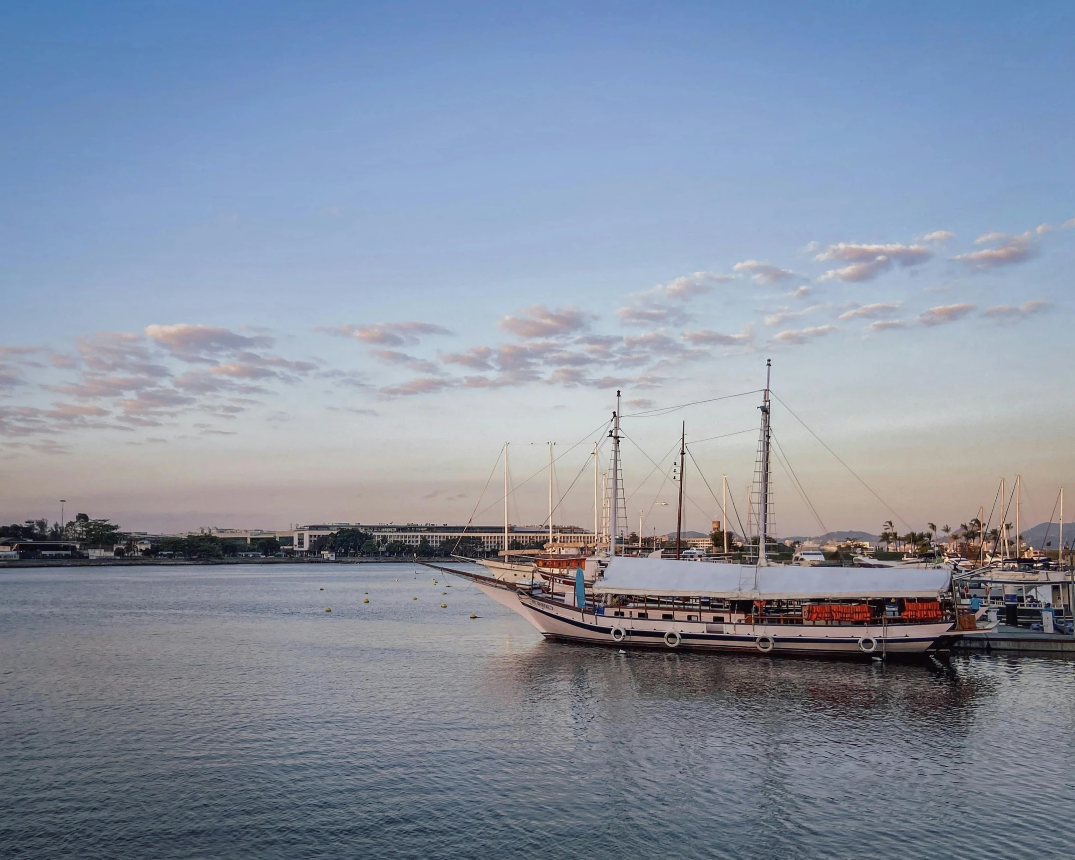 a boat that is sitting in the water, harbour in background, magic hour photography, ships with sails underneath, steamboat willy