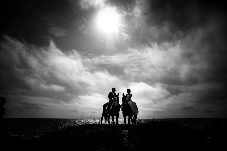 a couple of people riding on the backs of horses, a black and white photo, by John Hutton, unsplash, romanticism, sun coast, with dramatic sky, wedding, hasselblad photography