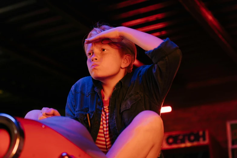 a man sitting on top of a red guitar, pexels, happening, sophia lillis, off camera flash, looking towards camera, light over boy