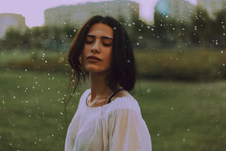 a woman standing in the rain with her eyes closed, inspired by Elsa Bleda, pexels contest winner, magical realism, brunette woman, beautiful jewish woman, beautiful lonely girl, wearing white clothes