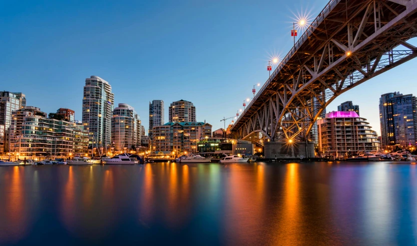 a bridge over a body of water with a city in the background, by Jason Felix, pexels contest winner, vancouver school, vibrant glow, slide show, upright, building along a river