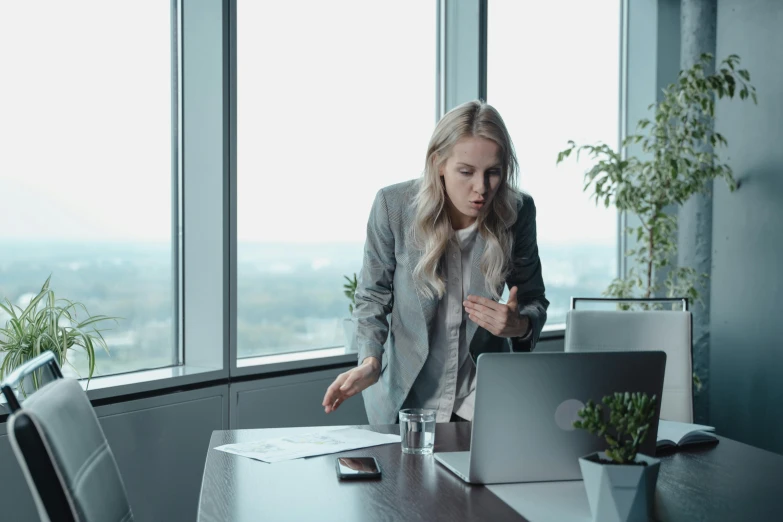 a woman standing in front of a laptop computer, pexels, figuration libre, concerned, in the office, screenshots, grey