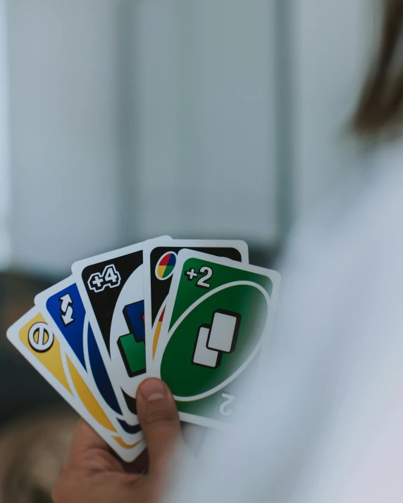 a person holding a game of uno uno uno uno uno uno uno uno uno uno uno uno, inspired by Aquirax Uno, unsplash, rainbow road, white marble interior photograph, non-binary, white sleeves