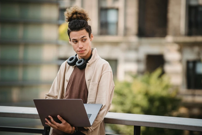 a woman with headphones holding a laptop, by Sebastian Vrancx, trending on pexels, renaissance, aboriginal australian hipster, on a rooftop, looking serious, androgynous male