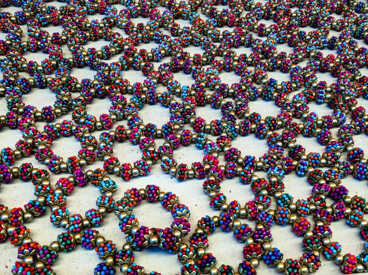 a table topped with lots of colorful beads, by Juliette Wytsman, pexels, kinetic pointillism, honeycomb halls, metal lace, shot with iphone 1 0, mauve and cinnabar and cyan