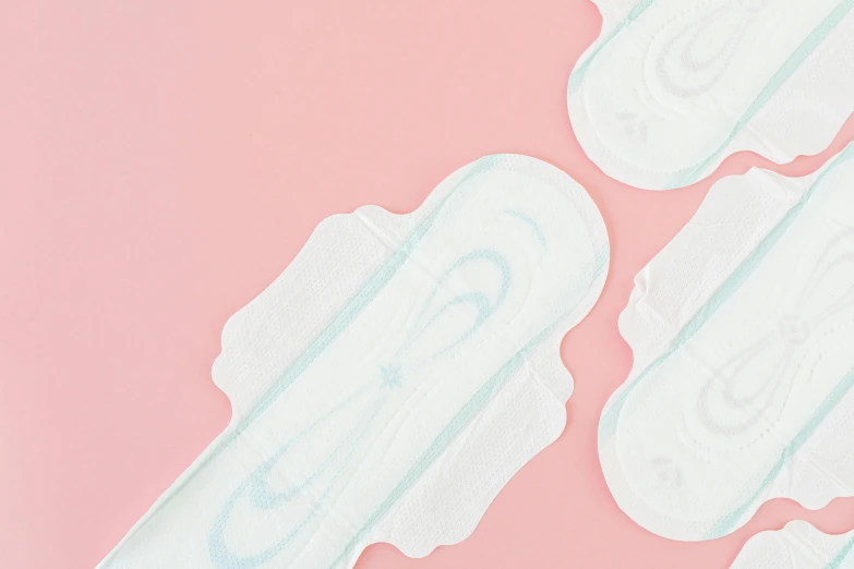 a group of sanitary pads sitting on top of a pink surface, detailed product image, arched back, white and pale blue toned, close-up on legs