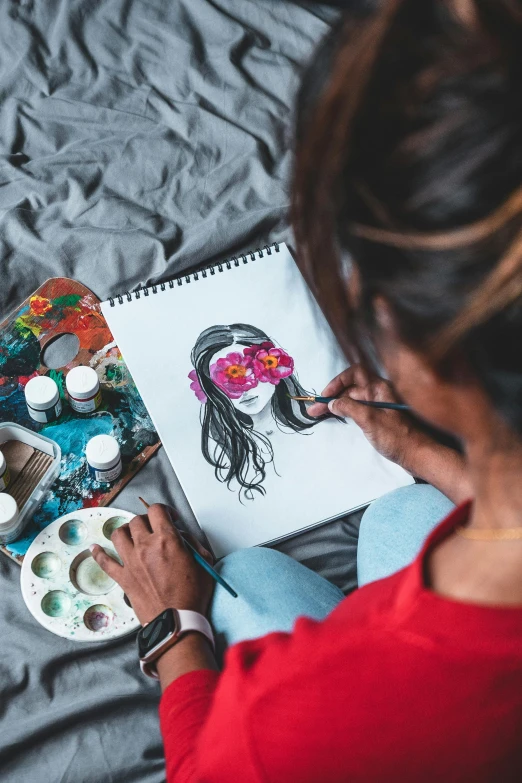 a woman sitting on a bed working on a painting, a watercolor painting, pexels contest winner, girl with a flower face, indian ink, flat lay, trending on artstion