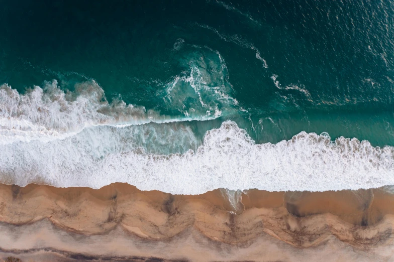 a large body of water next to a sandy beach, pexels contest winner, ocean spray, air shot, thumbnail, wall of water either side