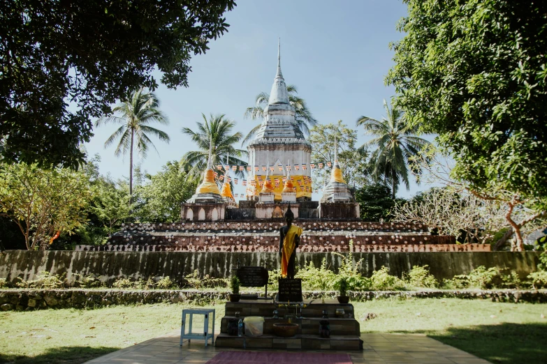 a statue sitting on top of a lush green field, in front of a temple, dug stanat, yoga, ceremony