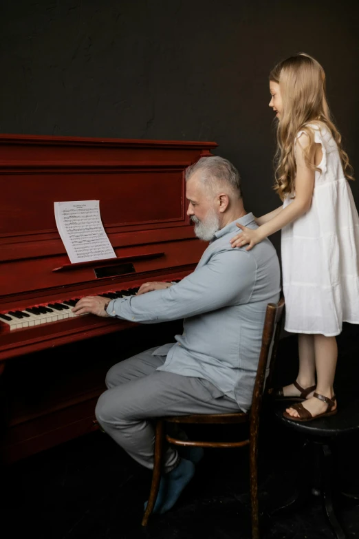 a little girl standing next to a man playing a piano, inspired by Edward George Handel Lucas, pexels contest winner, old man, profile image, white and red color scheme, knees upturned