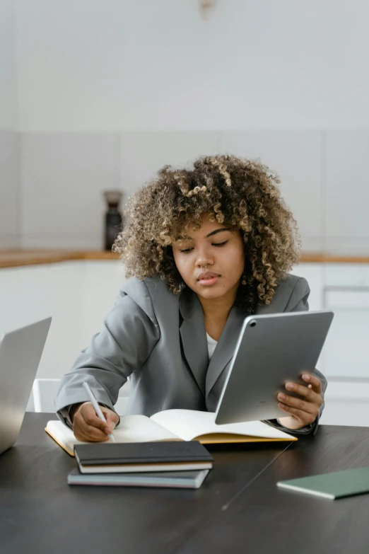 a woman sitting at a table with two laptops, by Carey Morris, trending on pexels, a teen black cyborg, holding a clipboard, wavy hair spread out, russian academic