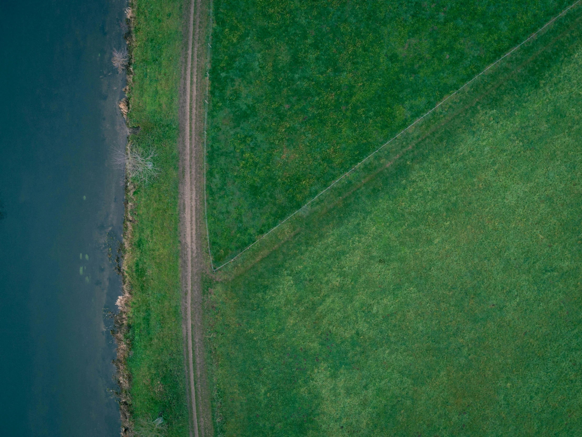 an aerial view of a road next to a body of water, by Attila Meszlenyi, pexels contest winner, land art, in a large grassy green field, square lines, cinematic shot ar 9:16 -n 6 -g, an abstract