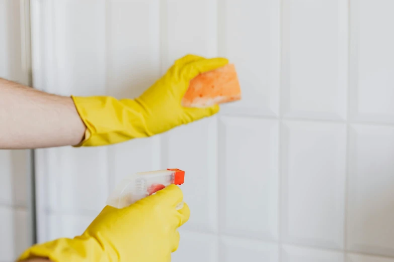 a person in yellow gloves cleaning a white tiled wall, a portrait, by Nicolette Macnamara, shutterstock, fan favorite, spraying blood, perfectly tileable, soap