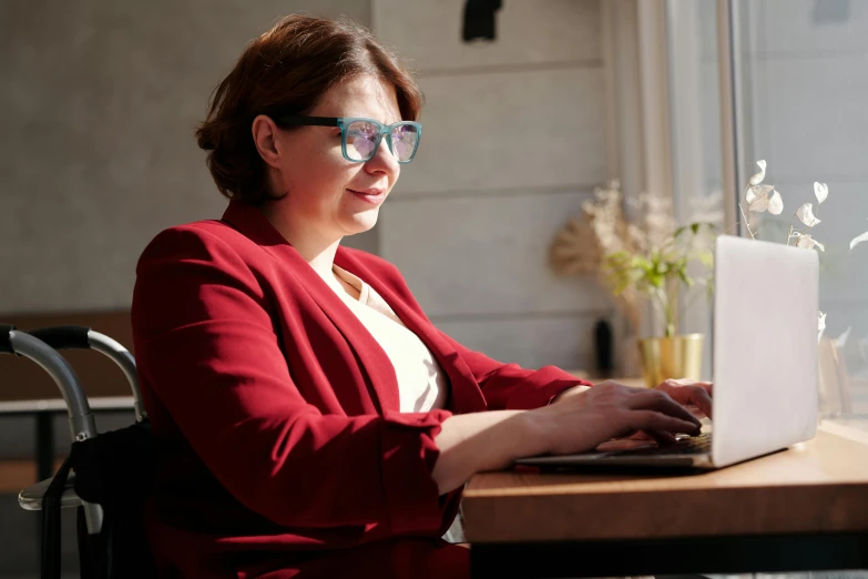 a woman sitting at a table using a laptop computer, a portrait, by Emma Andijewska, pexels, thick glasses, avatar image, nikolay georgiev, high quality image