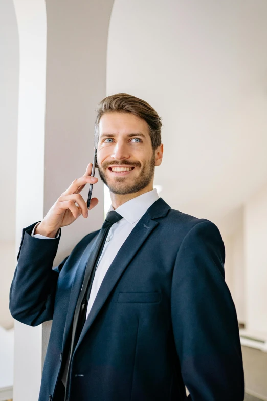 a man in a suit talking on a cell phone, posing for a picture