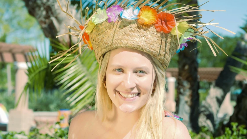 a close up of a person wearing a hat, tropical flowers, smiling at the camera, blonde swedish woman, orgnic headpiece