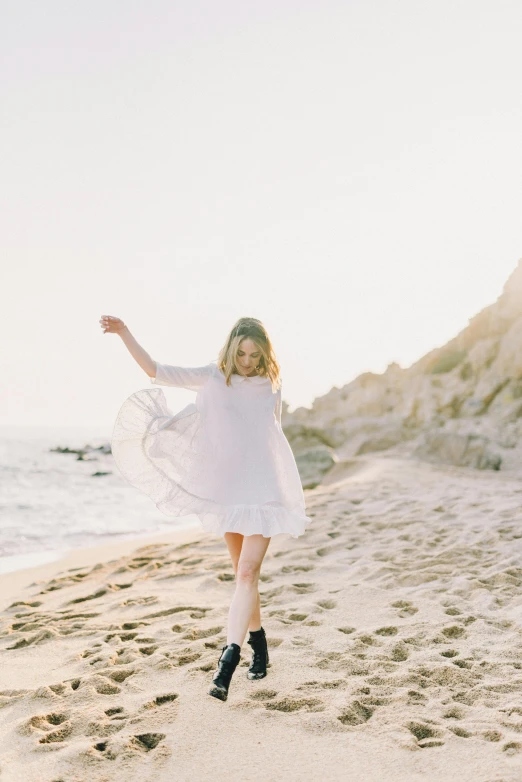 a woman standing on top of a sandy beach, girl in white dress dancing, sydney sweeney, goop, running freely