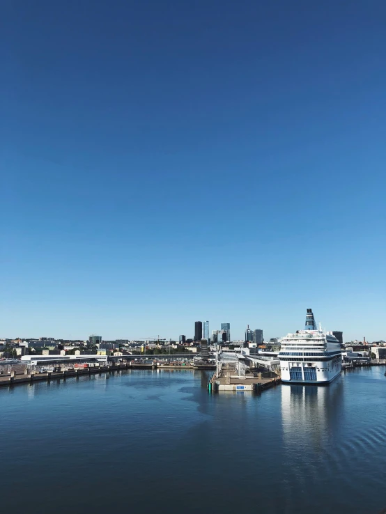 a boat in a body of water with a city in the background, blue sky, espoo, standing on a ship deck, thumbnail