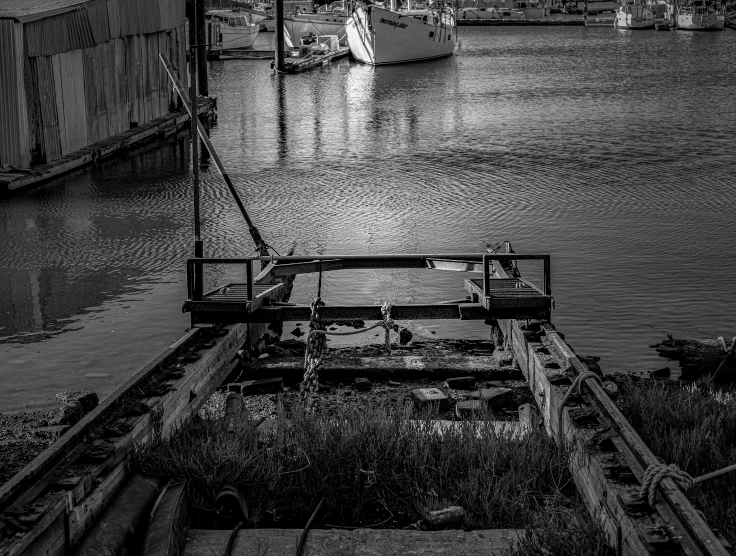 a black and white photo of boats in a harbor, a black and white photo, by Arnie Swekel, conceptual art, an abandoned, broken machinery, waterway, taken with sony alpha 9