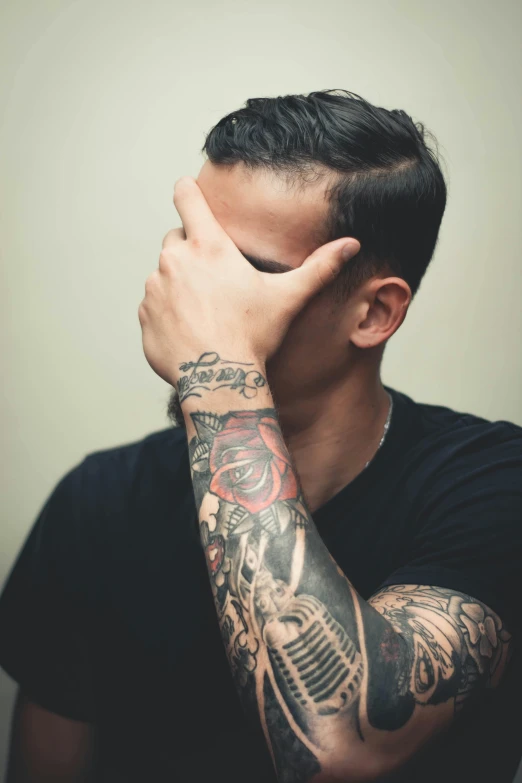 a man with a tattoo on his arm covering his face, trending on pexels, clinically depressed, lgbt, alex yanes, distraught