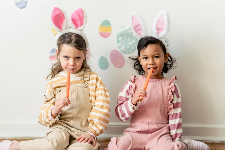 two little girls sitting on the floor eating carrots, inspired by Elsa Beskow, pexels, graffiti, with bunny rabbit ears, rainbow stripe backdrop, diverse costumes, photograph of april