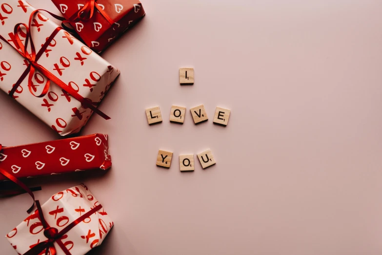 a pile of wrapped presents sitting on top of a table, a picture, letterism, i love you, background image, abcdefghijklmnopqrstuvwxyz, flatlay