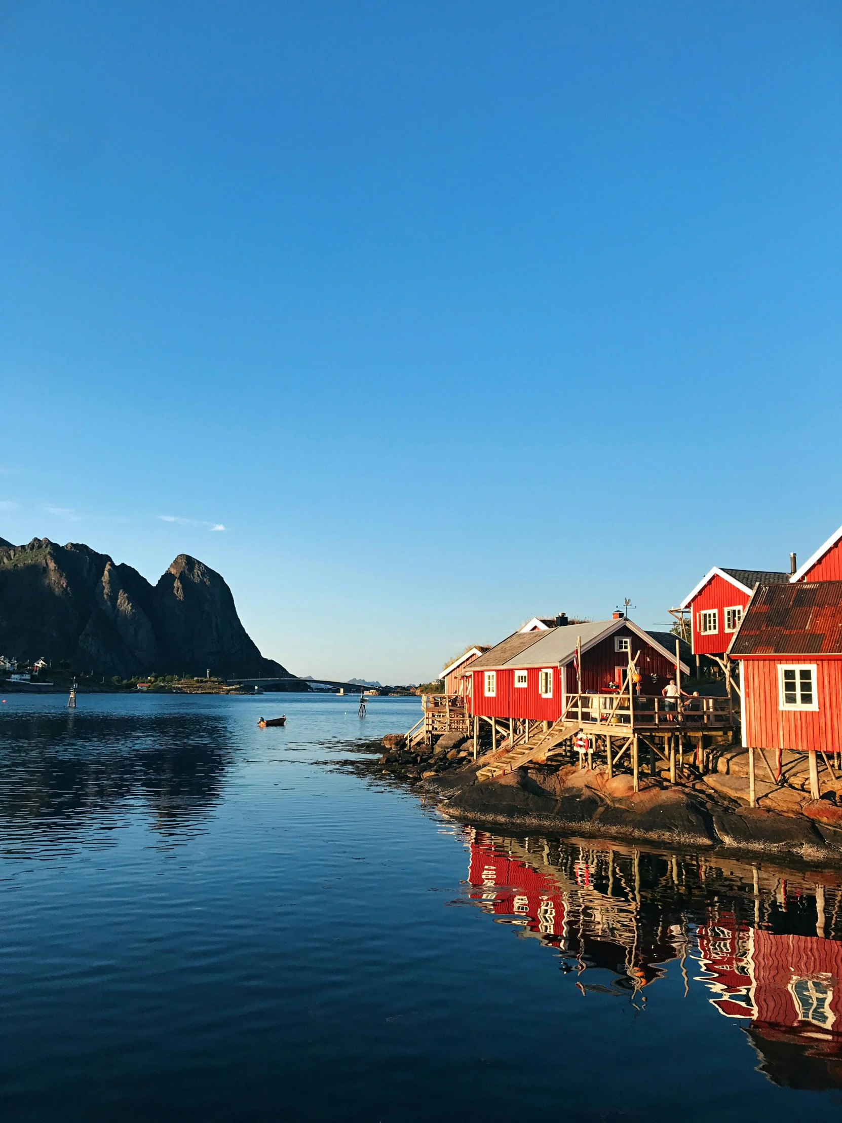 a group of red houses sitting on top of a body of water, fjords, late afternoon sun, next to the reflecting ocean, youtube thumbnail