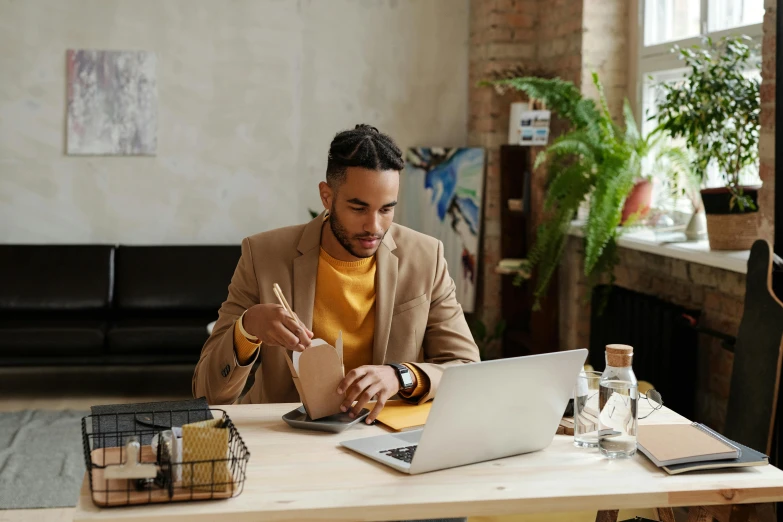 a man sitting at a table working on a laptop, pexels contest winner, ashteroth, wearing business casual dress, cardboard, aboriginal australian hipster