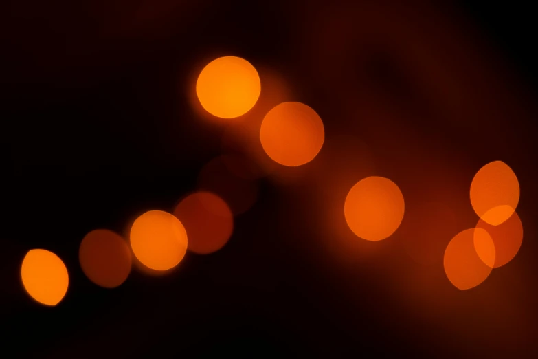 a blurry picture of some lights in the dark, pexels, orange hue, volumetric cinematic light, soft light - n 9, light circles