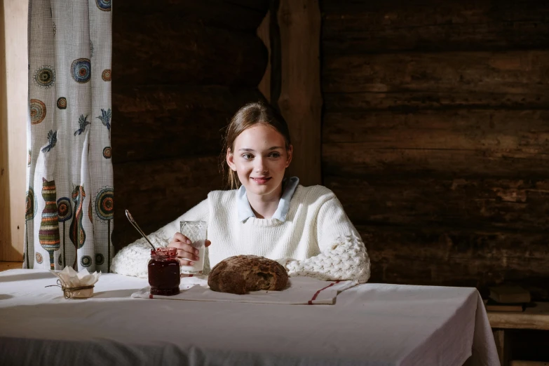 a woman sitting at a table with a plate of food, a portrait, inspired by Sigrid Hjertén, pexels contest winner, teenager girl, president of belorussia, bread, in a cabin