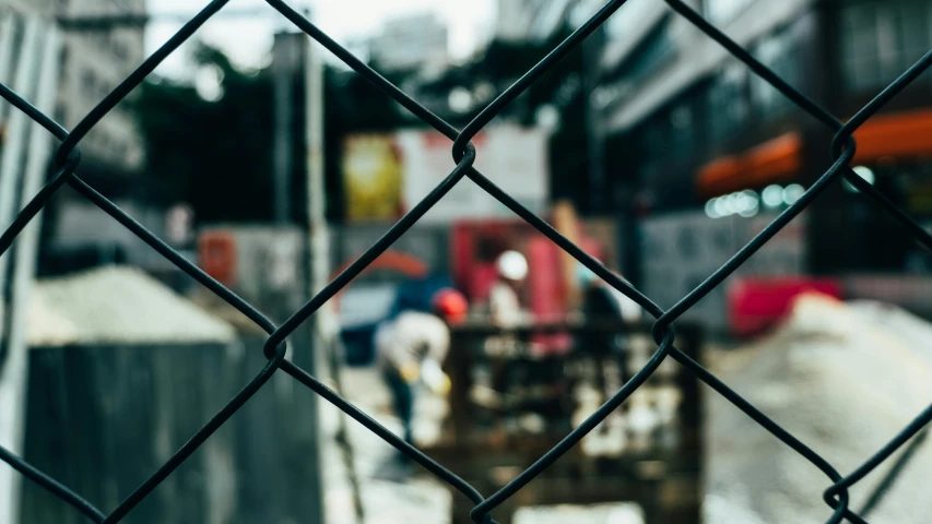 a view of a construction site through a chain link fence, pexels contest winner, street photo, background image, unblur, gritty image