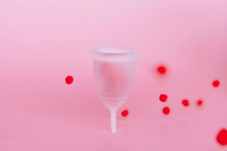 a glass filled with liquid sitting on top of a pink surface, plasticien, contracept, red nose, dissolution filter, silicone cover