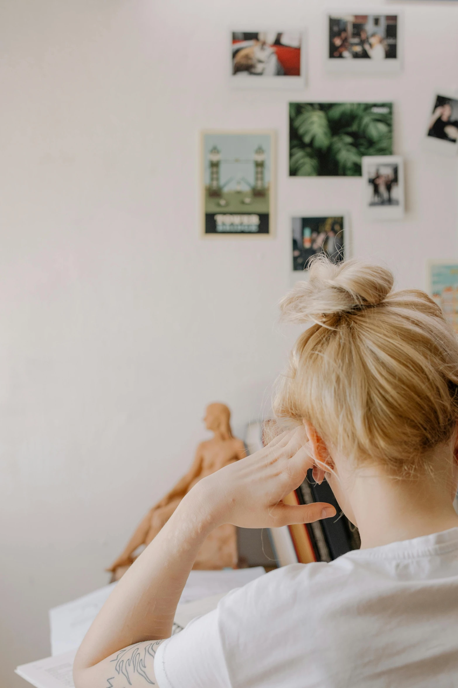 a woman sitting at a table in front of a laptop computer, trending on pexels, visual art, blond hair. ponytail, taking a picture, back of head, in the gallery