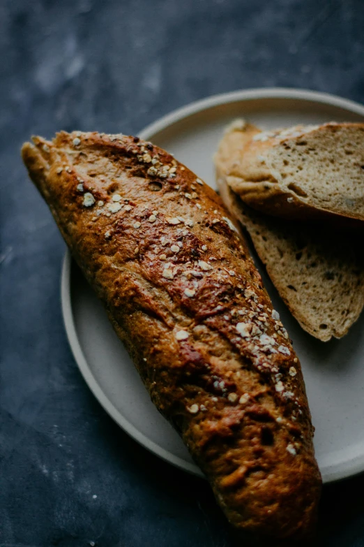 a loaf of bread sitting on top of a white plate, a portrait, unsplash, baking french baguette, mineral grains, thumbnail, no cropping