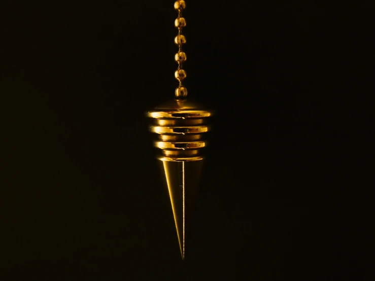 a golden pendulum hanging from a chain on a black background, by Adam Marczyński, hurufiyya, screw, 1 7 mm, spiked, light cone