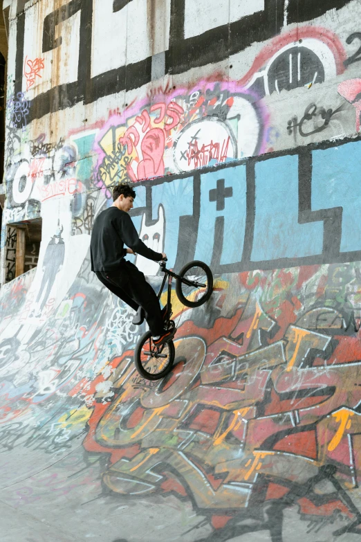 a man riding a bike up the side of a ramp, graffiti, circle pit, snacks, on a large marble wall, riding