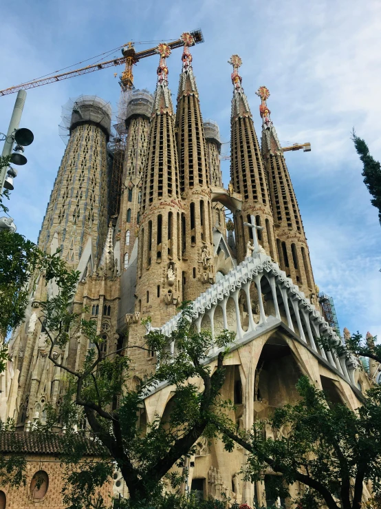 a group of people standing in front of a tall building, by Gaudi, three towers, front facing the camera, spire, shot from a distance