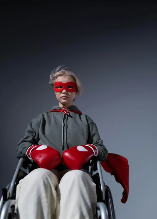 a woman in a red mask sitting in a wheelchair, inspired by Jens Ferdinand Willumsen, boxing gloves, 2019 trending photo, hero, super heroes