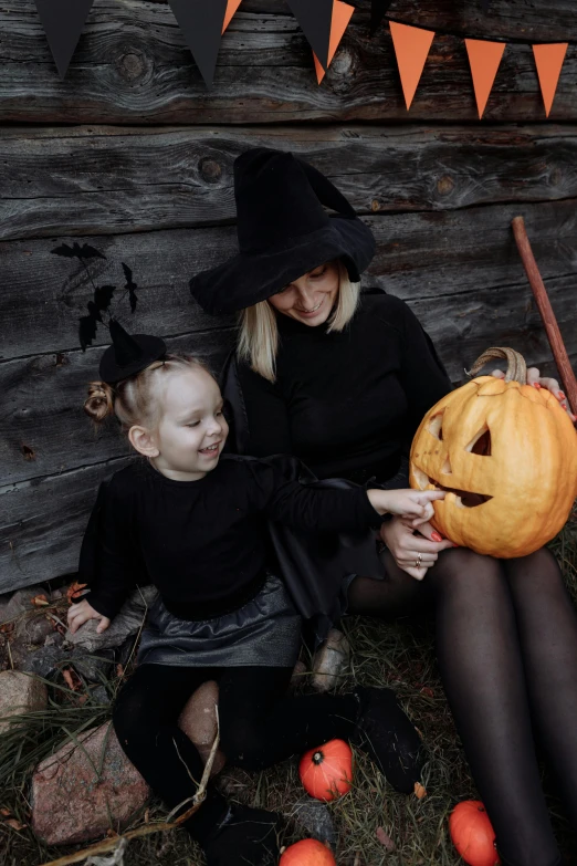 a woman sitting next to a little girl holding a pumpkin, pexels contest winner, black outfit, square, wooden magic wand, gif