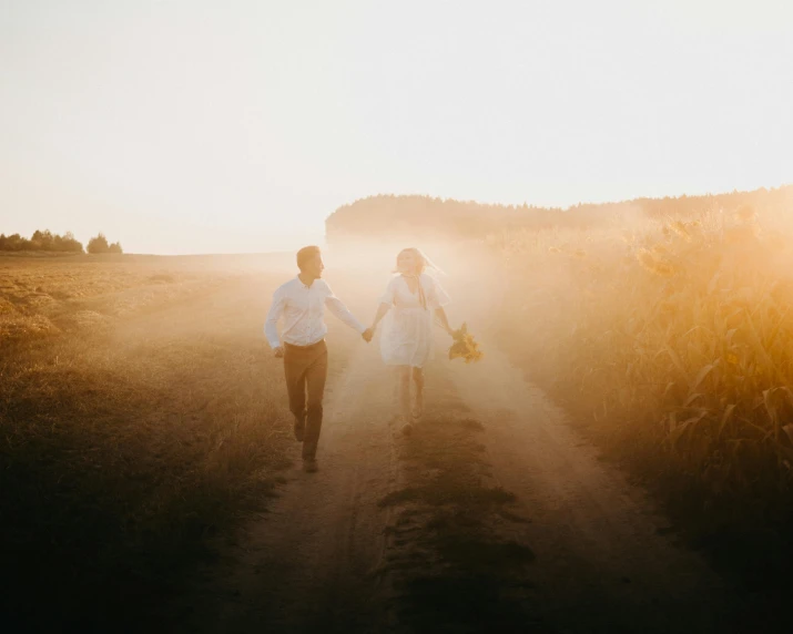 a couple walking down a dirt road holding hands, pexels contest winner, romanticism, morning glow, white, wedding, people running